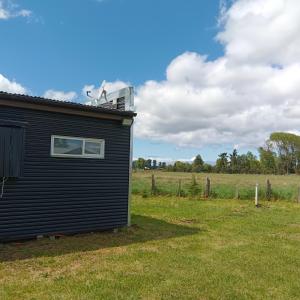 a black building in a field next to a fence at Entre Pinos y Volcanes in Frutillar