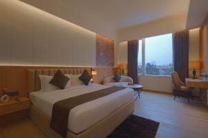 a hotel room with a large bed and a desk at Sterling Avante Chandigarh Mohali in Mohali +65 photos