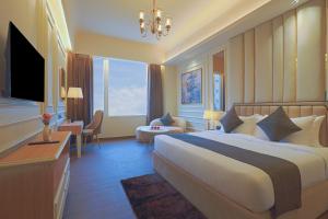 a hotel room with a large bed and a television at Sterling Avante Chandigarh Mohali in Mohali