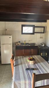 a kitchen with a table and a white refrigerator at Los Rochas, Barra de Chuy in Barra del Chuy
