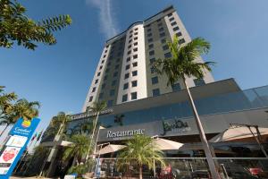 un edificio alto con palmeras delante en Comfort Hotel & Suítes Rondonópolis en Rondonópolis