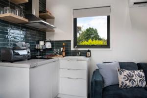 eine kleine Küche mit Sofa und Fenster in der Unterkunft Piccola Blu Tiny House in Hepburn