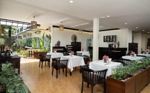 a restaurant with white tables and chairs and a piano at Indochine Sanctuary Boutique in Siem Reap