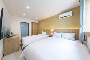 two beds in a hotel room with white sheets at Agabara Gangneung in Gangneung