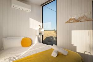 ein Schlafzimmer mit einem Bett mit gelbem Kissen und einem Fenster in der Unterkunft Billy Button by Tiny Away in Maindample