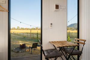 eine Veranda mit Tisch und Stühlen und Blick auf ein Feld in der Unterkunft Billy Button by Tiny Away in Maindample