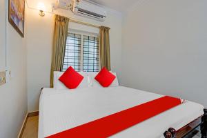 a bedroom with a large white bed with red pillows at Hotel O Le Fort in Trivandrum