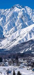 a snow covered mountain range with a town in front at 2 Peaks Snow Lodge in Hakuba +3 photos