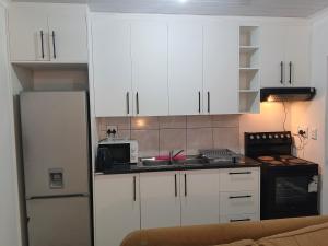 a kitchen with white cabinets and a refrigerator at Dwellers Double in Grassy Park