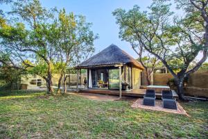 a small cabin in a yard with trees at LookOut Safari Lodge in Klipdrift