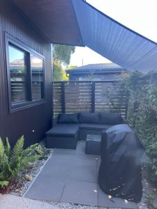 a patio with a blue couch under an umbrella at East Rock - Cosy Guesthouse in Kelvin Heights in Queenstown