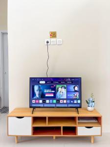 a flat screen tv sitting on top of a wooden entertainment center at SYARIAH - 3BR Homeyy by Sakura in Krawang