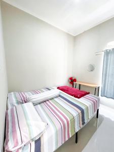 a bedroom with a bed with a striped blanket at SYARIAH - 3BR Homeyy by Sakura in Krawang