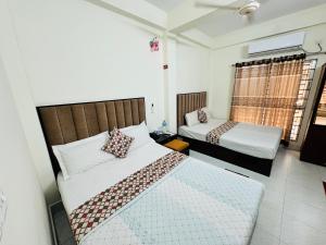 a bedroom with two beds and a window at Hotel Grand Shah Kamal in Sylhet