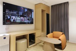 a room with a tv and a chair and a table at 부천 브라운도트 호텔 부천역점 in Sosa