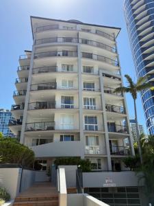 a tall building with a palm tree in front of it at San Mateo On Broadbeach in Gold Coast