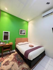 a bedroom with a green wall with a bed and a desk at The Cabin Tugu Hostel in Yogyakarta