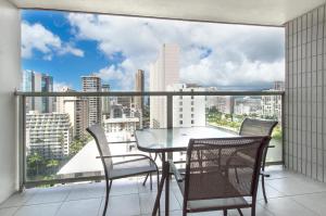 een tafel en stoelen op een balkon met uitzicht op de stad bij ISLAND COLONY STUDIO 1816 in Honolulu