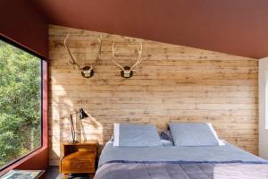 a bedroom with a wooden wall with a bed at Blackpool House - Stay Waiheke in Oneroa