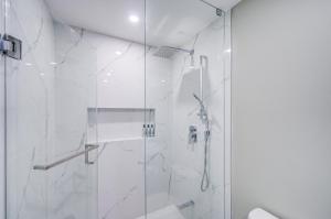 a white bathroom with a shower with a glass door at Cozy Studio with 2 Beds & Private Bathroom in Toronto