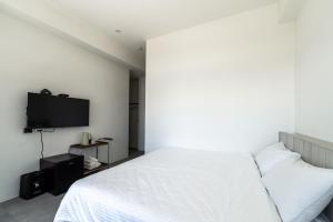 a bedroom with a white bed and a flat screen tv at IsShoNi B&B in Huxi