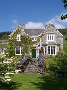 a large stone house with a green door at Penmachno Hall - self catering suite in Betws-y-coed