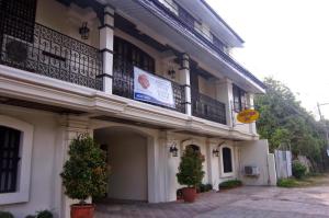 a white building with a balcony and two potted plants at Metro Vigan Inn MAIN in San Vincente