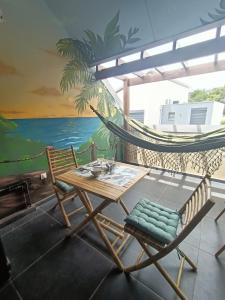 a hammock and a table and chair on a balcony at La Cabane du lagon atypique et accès à la plage in La Saline les Bains