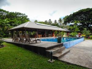 a swimming pool with chairs and a gazebo at Taveuni Dive Resort in Waiyevo