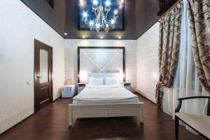 a bedroom with a white bed and a chandelier at Hotel Kupecheskiy Dom in Tomsk