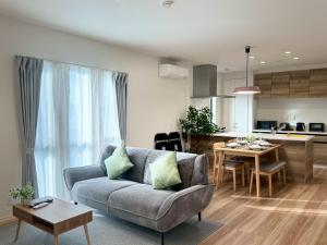 a living room with a couch and a kitchen at Akikawa Waifu 2 プレミアム木造 一棟貸切ヴィラ in Kikuchi