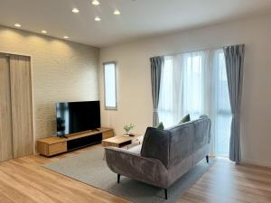a living room with a couch and a television at Akikawa Waifu 2 プレミアム木造 一棟貸切ヴィラ in Kikuchi