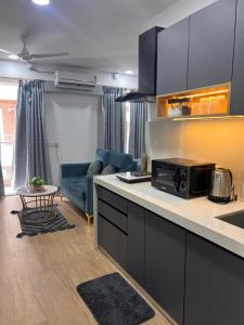 a kitchen and living room with a couch and a microwave at NEON - Nirvana Stays With PVT Balcony -1 Km from Airport in Pune