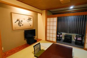 a dining room with a table and a tv and a window at Fuji Yamanakako Hotel in Yamanakako