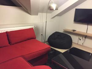 a living room with a red couch and a tv at Two Level Apartment near Gondola in Gudauri