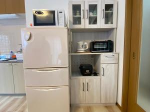 a kitchen with a white refrigerator and a microwave at コテージオギー in Nasu