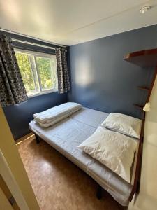 a bed in a bedroom with a blue wall at Camping L'Amandier in Gigors +26 photos