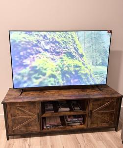 a flat screen tv sitting on top of a wooden entertainment center at Private 1BR Suite with Kitchen, Laundry, Parking & 1 Gigabit Internet in Whitehorse