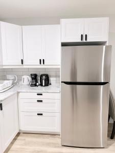 a stainless steel refrigerator in a kitchen with white cabinets at Private 1BR Suite with Kitchen, Laundry, Parking & 1 Gigabit Internet in Whitehorse