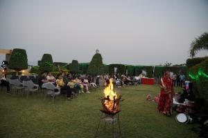 a group of people sitting around a fire in a field at Mount Valley Resort in Kumbhalgarh