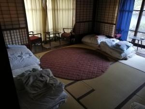 a room with two beds and a rug on the floor at z Authentic Trad Villa experience in Onomichi