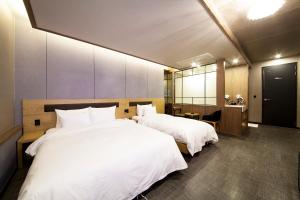 a hotel room with two beds with white sheets at Jinju Kai Hotel in Jinju