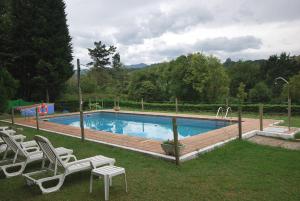 a swimming pool with two lawn chairs and a table at Vega Del Sella in Arriondas