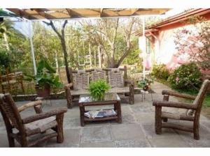 a patio with wooden benches and a table and trees at Casa Plaza Los Caballos in Olmué