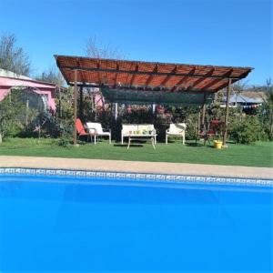 a pergola with chairs and tables next to a pool at Casa Plaza Los Caballos in Olmué