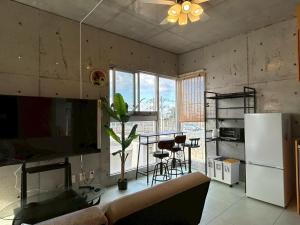 a kitchen with a couch and a table and a refrigerator at オランウータンApple House Ginowan in Ginowan