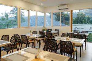 a dining room with tables and chairs and windows at Eeleem Resorts and Spa, Munnar in Anachal
