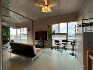 a living room with a ceiling fan and a couch and a table at オランウータンApple House Ginowan in Ginowan