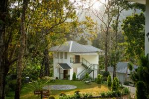 a white house in the middle of a forest at Eeleem Resorts and Spa, Munnar in Anachal