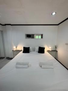 a bedroom with a large white bed with two chairs at Pathaya in Ban Kata